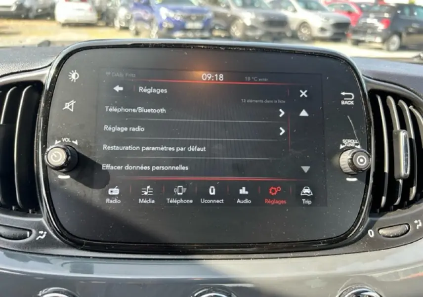 Écran tactile central de la Fiat 500C 2021 affichant le menu Réglages, avec commandes autour et tableau de bord gris.