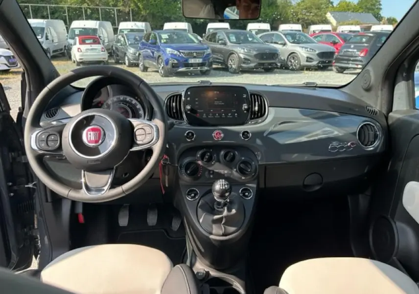 Vue intérieure avant de la Fiat 500C gris et rouge, avec tableau de bord brillant et volant multifonction noir.