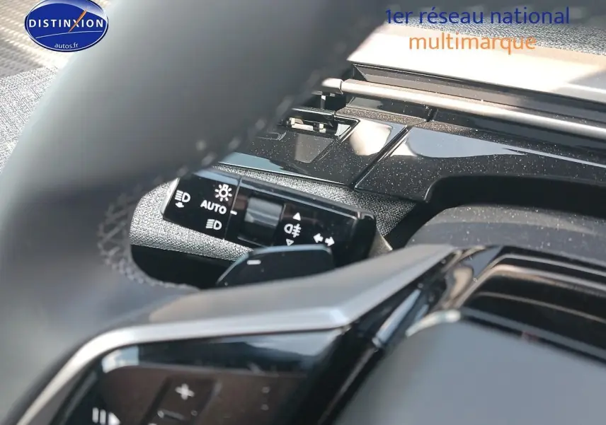 Détail du commodo d’éclairage et partie du volant cuir noir du Peugeot 3008 1.2 hybrid 145 allure, intérieur moderne.