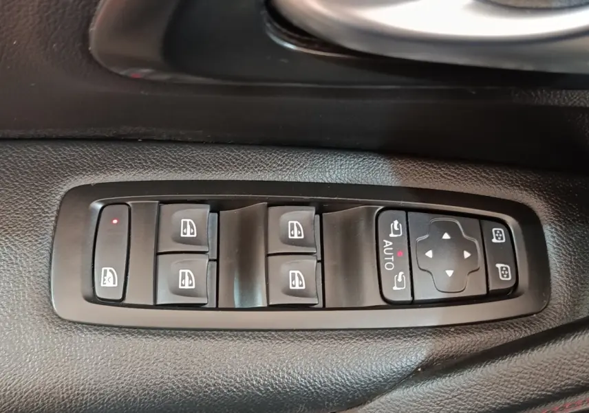 Vue rapprochée des commandes de lève-vitres et rétroviseurs sur la porte côté conducteur du Renault Kadjar blanc.