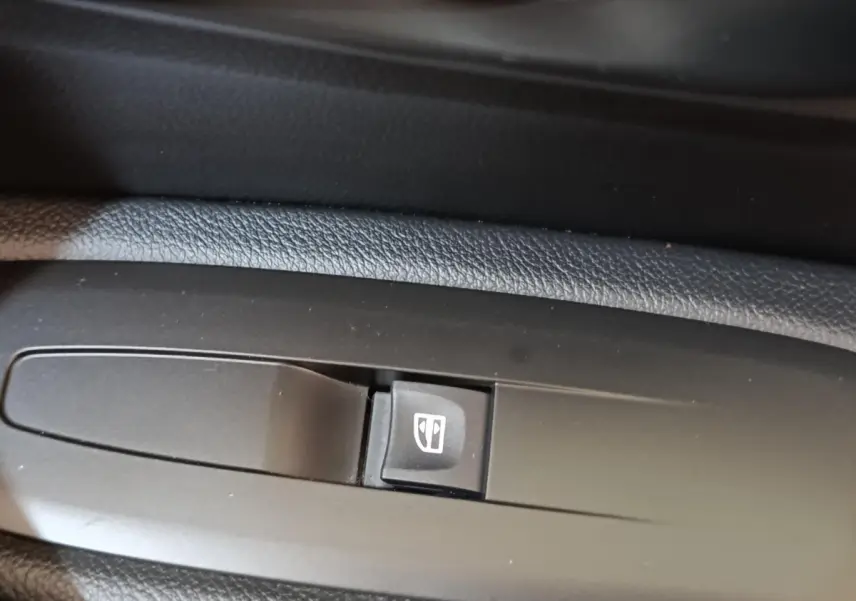 Gros plan sur le bouton de commande de la vitre électrique côté conducteur du Renault Kadjar blanc, version Black Edition.