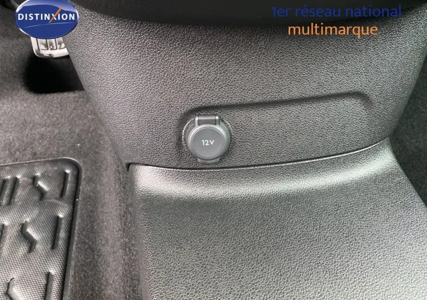 Prise 12V en gros plan sur la console centrale noire du Citroën Berlingo Fourgon blanc, vue intérieure rapprochée.