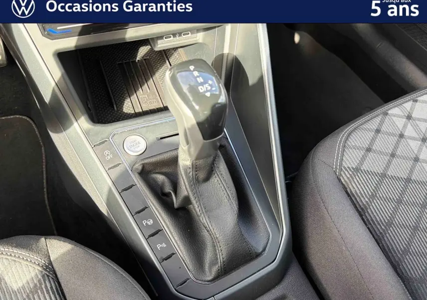 Gros plan sur la console centrale du Volkswagen Taigo gris, mettant en valeur le levier de vitesses automatique et le siège avant droit.