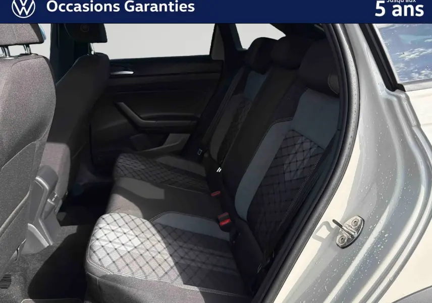 Vue intérieure côté droit des sièges arrière gris à motifs du Volkswagen Taigo 2025 avec porte ouverte et carrosserie grise visible.