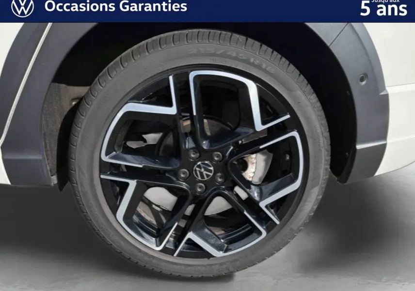 Gros plan sur la jante alliage noir et argent 18 pouces du Volkswagen Taigo gris, avec pneu 215/45 R18 visible côté arrière.