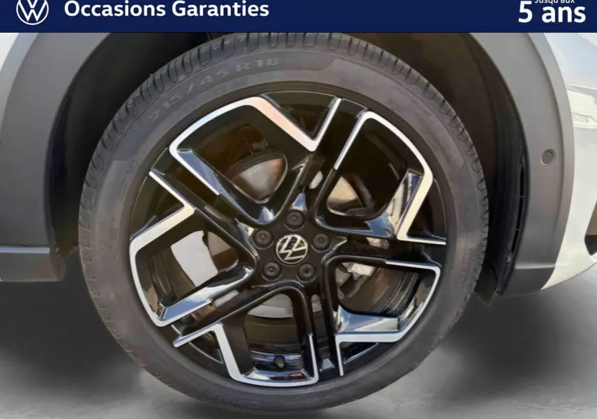 Gros plan sur la jante alliage noire et argent 18 pouces du Volkswagen Taigo gris, avec pneu 215/45 R18 visible.