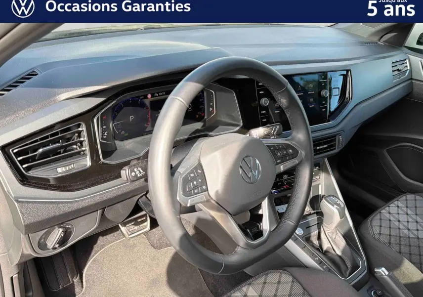 Vue intérieure du poste de conduite du Volkswagen Taigo gris, avec volant cuir multifonctions et écran tactile central.