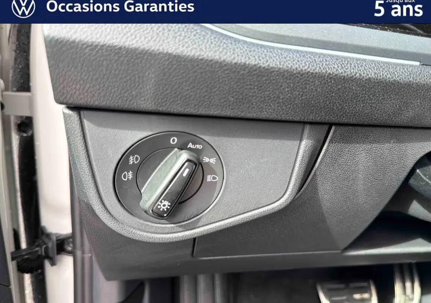 Gros plan sur le bouton de commande des phares à gauche du tableau de bord du Volkswagen Taigo gris.