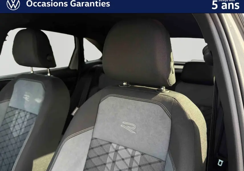 Gros plan sur les sièges avant gris du Volkswagen Taigo 2025 avec surpiqûres et logo R brodé.