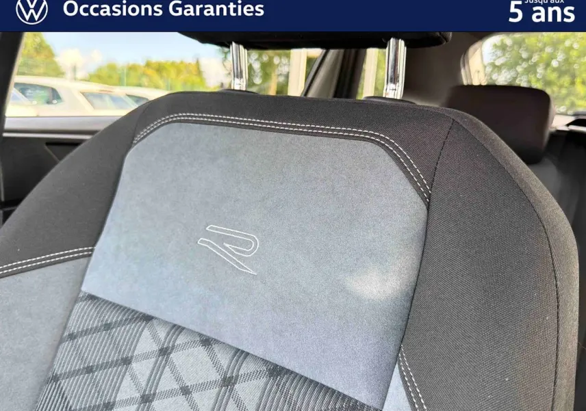 Détail de l’appui-tête avant gris et noir avec surpiqûres blanches et logo "R" brodé sur la Volkswagen Taigo.