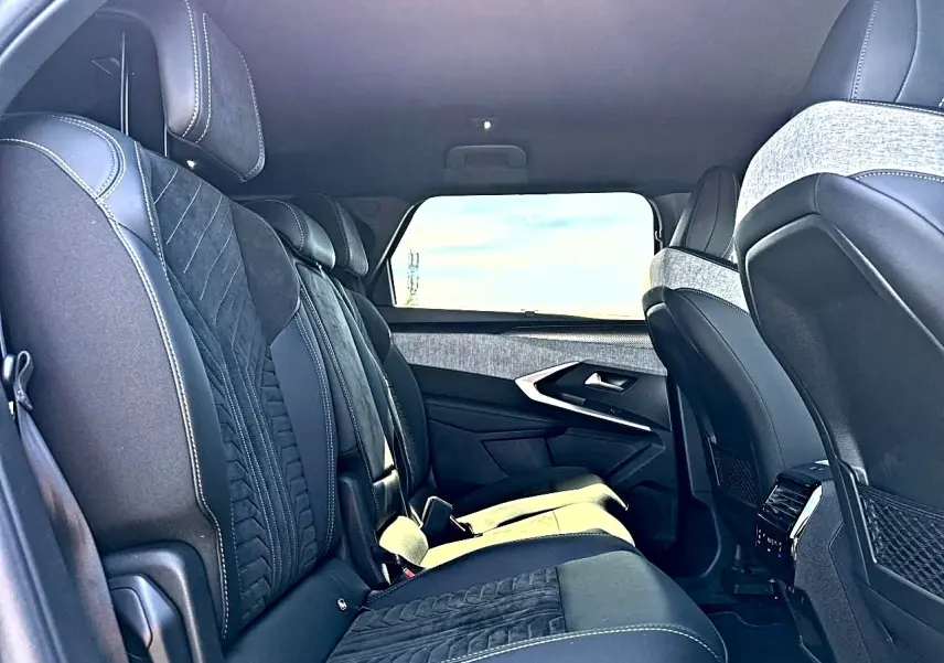 Vue latérale intérieure du rang 2 du Peugeot 5008 Hybrid 145 GT noir, avec sièges en cuir et tissu noir et gris.