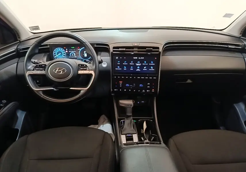 Vue intérieure avant du Hyundai Tucson 2021, tableau de bord noir avec écran tactile central et volant multifonctions.