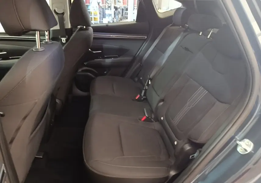 Vue intérieure côté droit des sièges arrière noirs du Hyundai Tucson 2021 hybride, avec ceintures et appuie-têtes visibles.