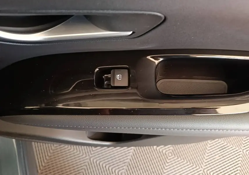 Gros plan sur la commande de verrouillage des vitres côté conducteur du Hyundai Tucson bleu, intérieur noir.