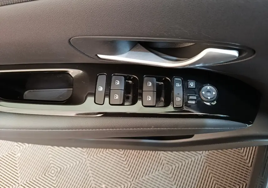 Gros plan sur la commande des vitres et rétroviseurs côté conducteur d’un Hyundai Tucson bleu, intérieur noir.