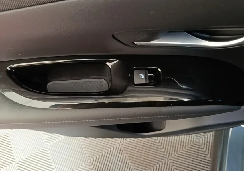 Gros plan sur la commande de verrouillage de porte côté conducteur, finition noire brillante dans l’habitacle du Hyundai Tucson bleu.