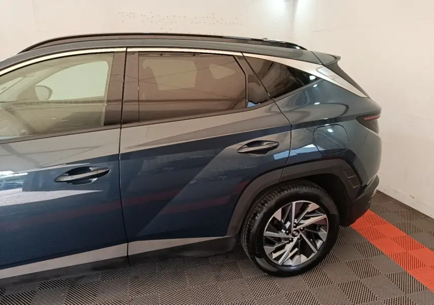 Vue latérale droite du Hyundai Tucson bleu avec jante alliage et toit noir dans un garage fermé.