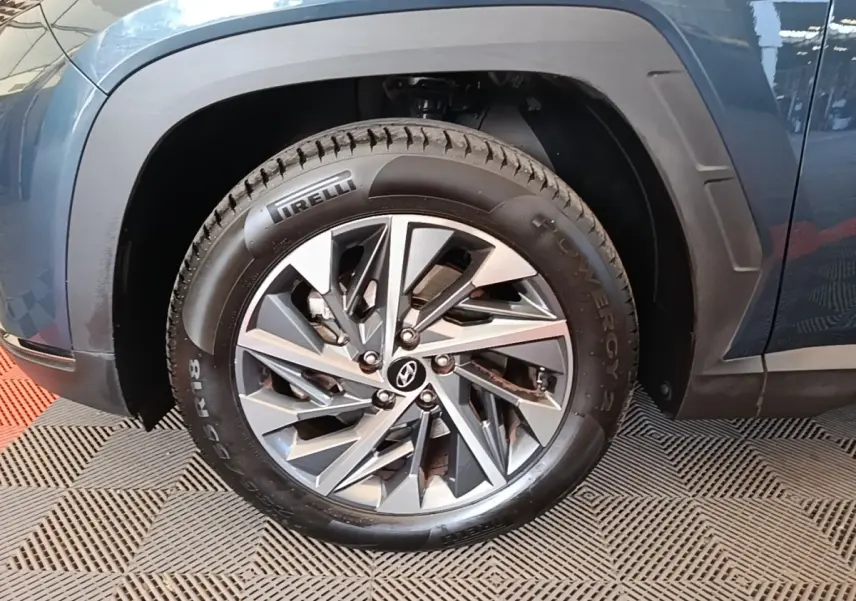 Gros plan sur la roue avant gauche du Hyundai Tucson bleu, avec jante alliage et pneu Pirelli visible.