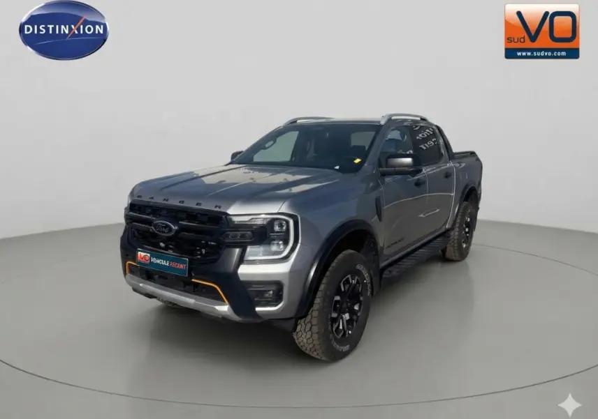 Ford Ranger gris en vue 3/4 avant droit avec barres de toit et jantes alliage noires.