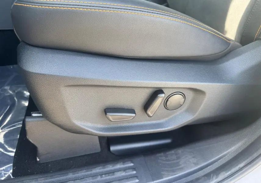 Gros plan sur les commandes de réglage électrique du siège avant droit en cuir noir avec surpiqûres orange du Ford Ranger gris 2025.