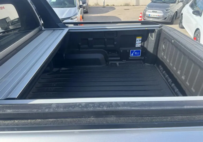 Vue rapprochée de la benne arrière grise du Ford Ranger 2025 avec barres de toit et ridelle ouverte.