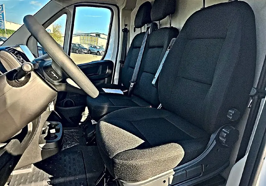 Vue intérieure côté conducteur du Peugeot Boxer Fourgon L2h2 2026, montrant les sièges noirs et le volant.