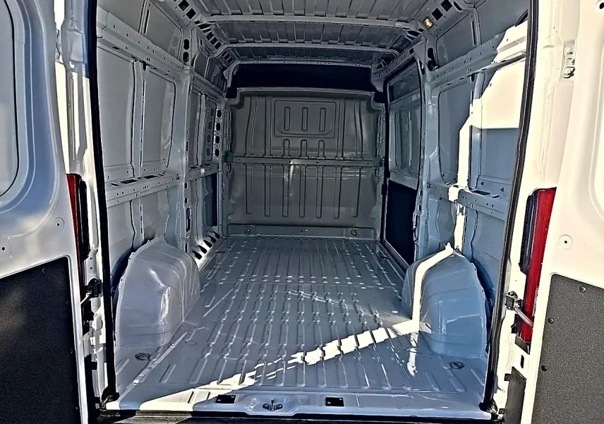 Vue intérieure arrière du fourgon blanc Peugeot Boxer L2h2 2026, montrant l'espace de chargement vide et la cloison pleine.