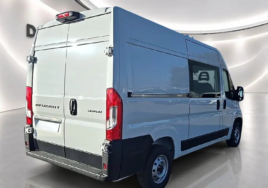 Vue 3/4 arrière droite d’un Peugeot Boxer Fourgon blanc avec porte latérale coulissante et double portes arrière ouvertes.