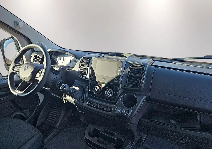 Vue intérieure du tableau de bord du Peugeot Boxer Fourgon blanc, avec volant, écran tactile et commandes manuelles visibles.