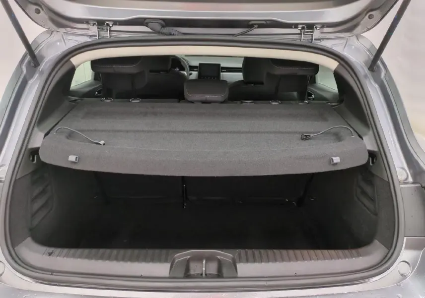 Coffre ouvert vu de l'arrière d'une Renault Clio 2024 gris foncé avec cache-bagages et sièges arrière.
