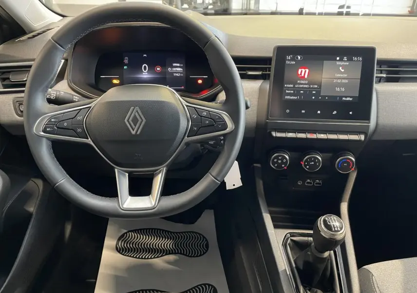 Vue intérieure centrée sur le volant et la console centrale de la Renault Clio 2024 avec levier de vitesse manuel.