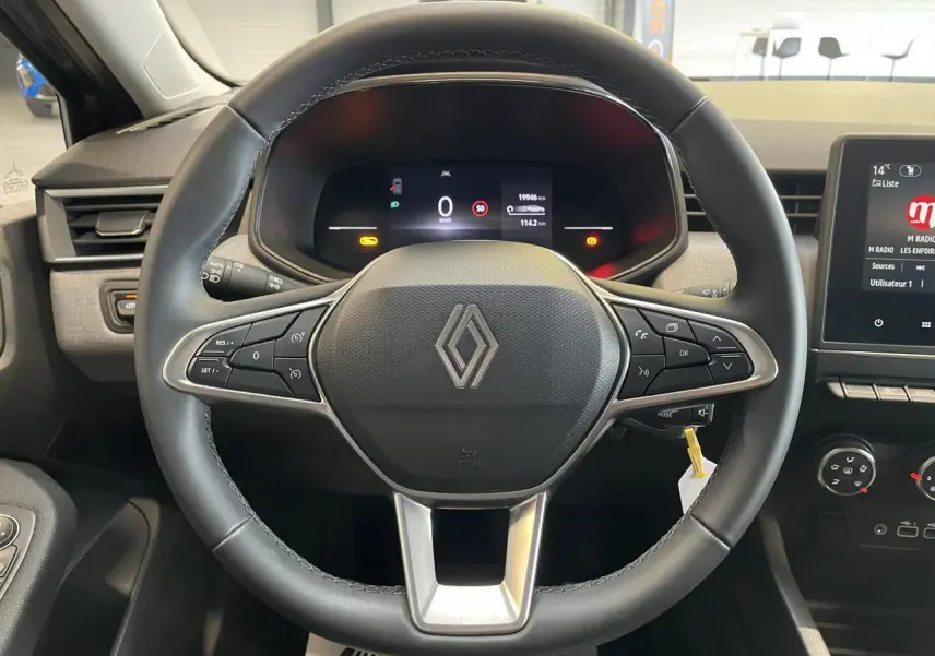 Vue centrée sur le volant noir de la Renault Clio 2024 avec tableau de bord numérique et commandes intégrées.