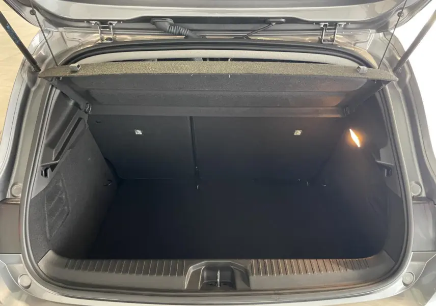 Coffre ouvert vu de dessus d'une Renault Clio 2024 gris foncé, avec éclairage intérieur et habillage noir.