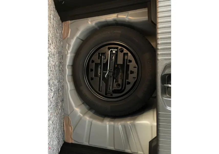 Gros plan sur la roue de secours tôle noire dans le coffre gris foncé de la Renault Clio 2024.