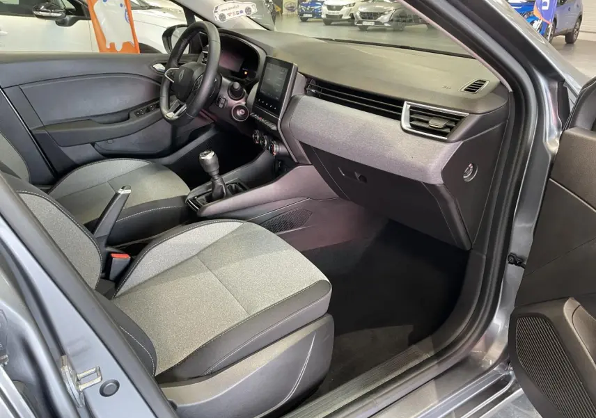 Vue intérieure côté conducteur de la Renault Clio gris foncé 2024 avec sellerie tissu gris et tableau de bord moderne.