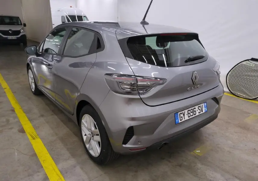 Renault Clio gris foncé vue 3/4 arrière droit, avec feux LED et jantes alliage 16 pouces en intérieur garage.