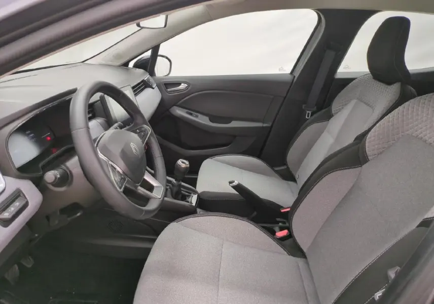 Vue intérieure côté conducteur de la Renault Clio 2024, sièges tissu gris et volant multifonction noir.