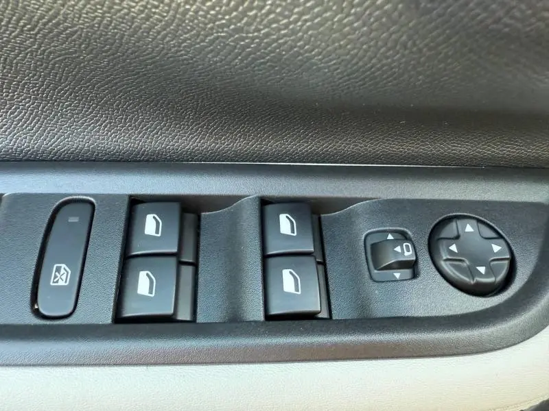 Gros plan sur les commandes de lève-vitres et réglage des rétroviseurs côté conducteur de la Citroën C3 Electrique noir Perla Nera.