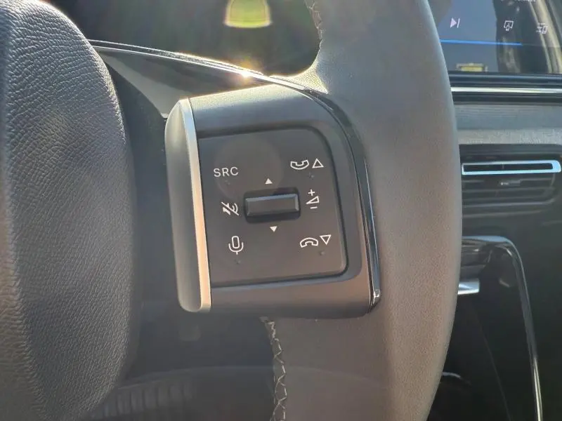 Gros plan sur les commandes audio et téléphone au volant noir de la Citroën C3 électrique 2025, intérieur moderne.