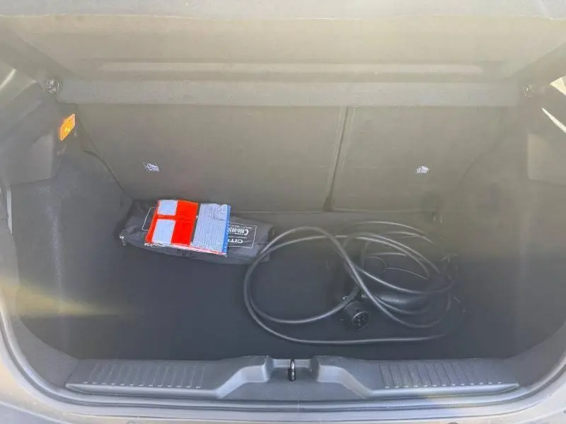 Coffre ouvert de Citroën C3 électrique noir Perla Nera, vue de dessus montrant câble de recharge et kit de sécurité.