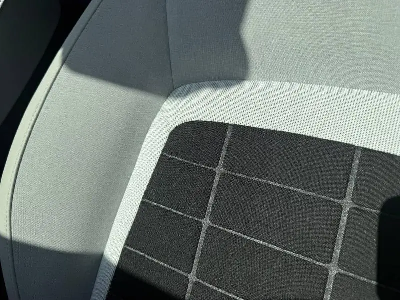 Gros plan sur le tissu bicolore noir et clair du siège avant de la Citroën C3 électrique 2025.