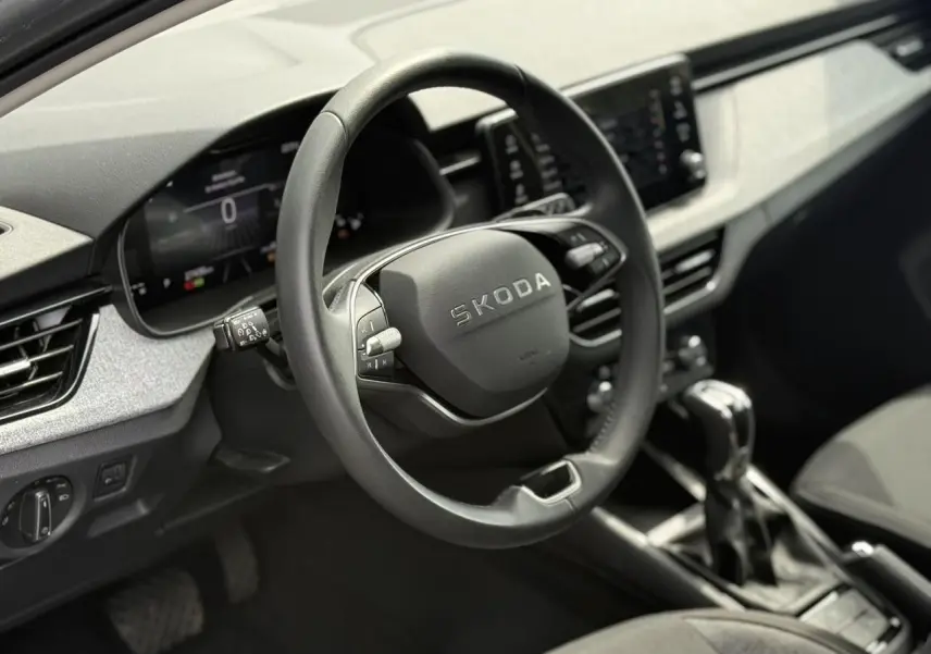 Vue intérieure centrée sur le volant noir de la Skoda Scala 2025 avec tableau de bord digital et levier de vitesse automatique.
