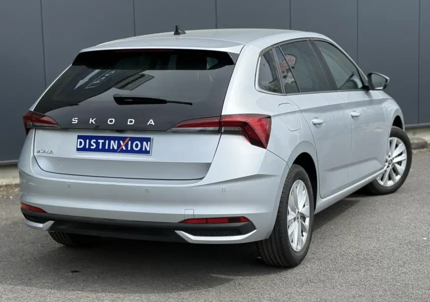 Vue 3/4 arrière droite d'une Skoda Scala TSI 116 DSG7 gris reflex avec vitres surteintées et jantes alliage 16 pouces.