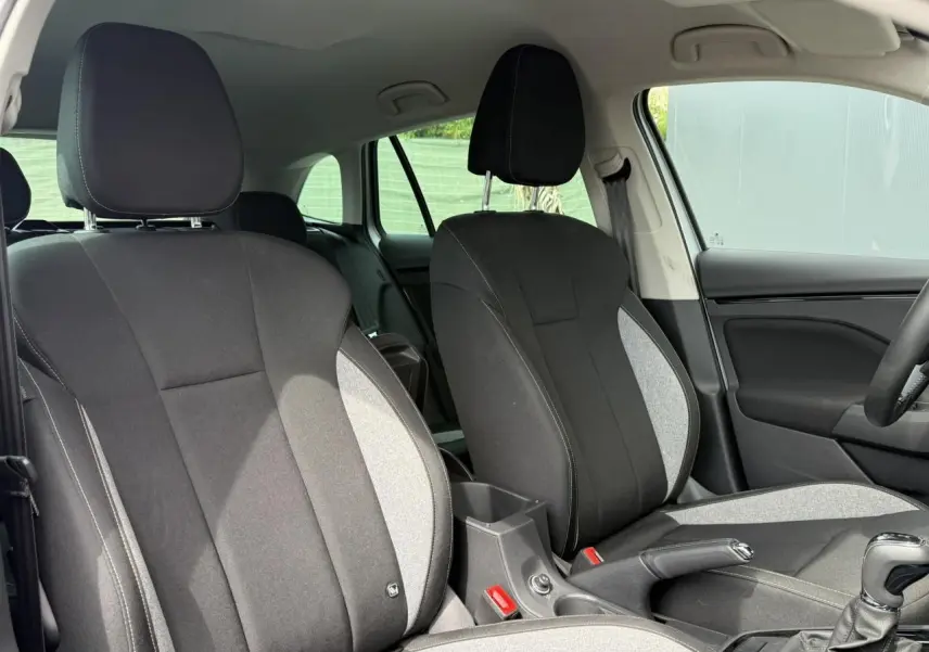 Vue intérieure côté avant droit du Skoda Scala TSI 116 DSG7, sièges tissu noir et gris avec surpiqûres contrastées.