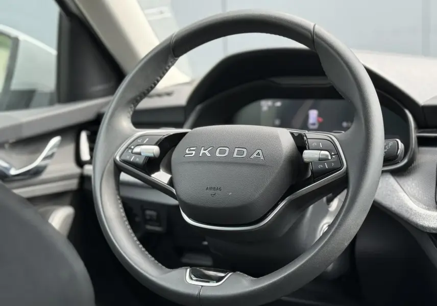 Vue rapprochée du volant cuir multifonctions SKODA de la Scala TSI 116 DSG7, avec tableau de bord numérique en arrière-plan.