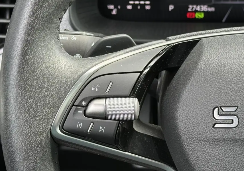 Gros plan sur la partie gauche du volant noir de la Skoda Scala 2025 avec commandes audio et molette métallique.