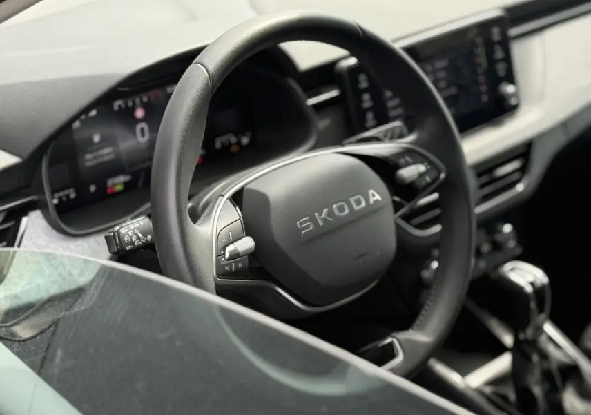 Vue rapprochée du volant en cuir multifonctions de la Skoda Scala 2025, avec tableau de bord numérique en arrière-plan.