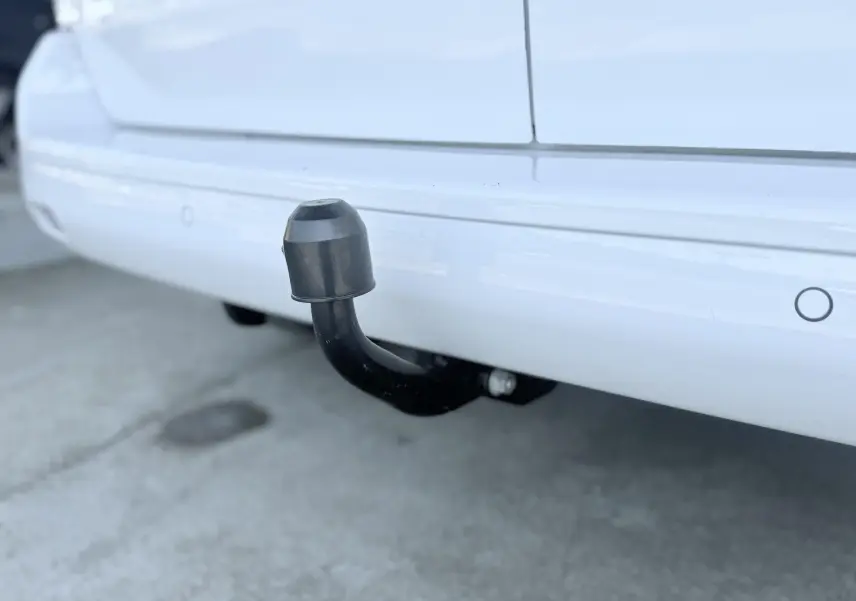 Gros plan sur l'attelage noir fixé au pare-chocs arrière blanc du Peugeot Expert Cabine Approfondie.