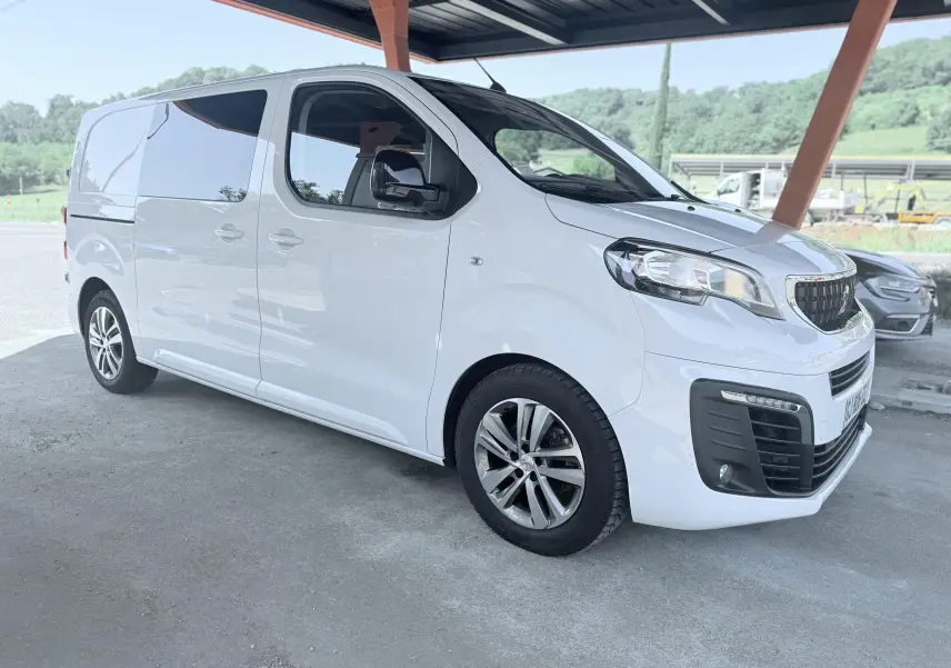 Peugeot Expert cabine approfondie blanc, vue 3/4 avant droit sous abri avec jantes alliage et vitres teintées.