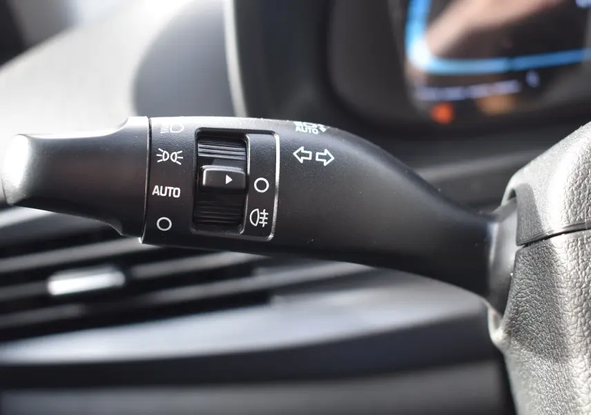 Gros plan sur la commande de clignotants et phares à gauche du volant dans l’habitacle d’une Hyundai i20 2025.